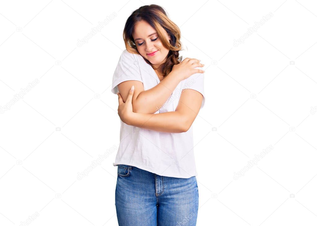 Young beautiful caucasian woman wearing casual white tshirt hugging oneself happy and positive, smiling confident. self love and self care 