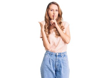 Sarışın, genç, beyaz, güzel bir kadın. Günlük giysiler giyiyor. Parmaklarını dudaklarına dayayıp sessiz olmak istiyor. sessizlik ve gizli konsept. 