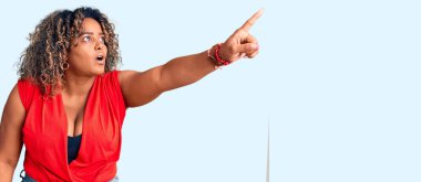 Genç Afro-Amerikan artı cüsseli kadın kolsuz tişörtlü, kolsuz, parmakları önde, ağzı açık, şaşırmış, ön tarafta bir şey var. 