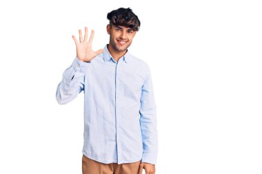 Gündelik tişört giyen genç İspanyol adam beş numarayı gösterip işaret ederken kendinden emin ve mutlu gülümsüyor.. 