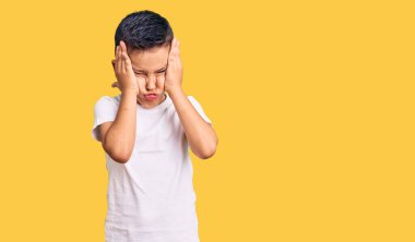 Küçük şirin çocuk günlük beyaz tişört giyiyor. Baş ağrısı çekiyor. Acı ve migren yüzünden çaresiz ve stresli. Eller başının üstünde.. 