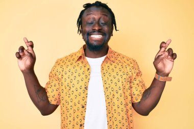 Saçları örgülü genç Afro-Amerikalı adam umut ve gözleriyle gülümseyerek el kol hareketi yapıyor. Şans ve batıl inançlar. 