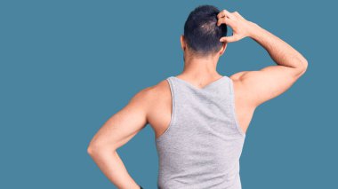 Mayolu ve kolsuz tişörtlü genç bir adam tersten şüpheyi kafa kafaya düşünüyor. 