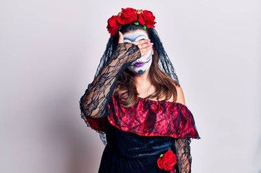 Genç bir kadın, ölü kostümünü beyaz gözlerinin üstüne giymiş. Elleriyle gözlerini kapatmış, ciddi ve üzgün görünüyor. Görme, saklama ve reddetme konsepti 