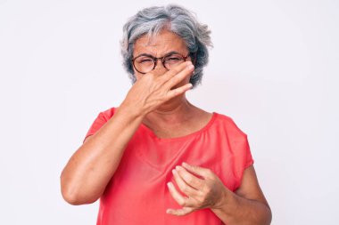 Son sınıf Latin kökenli, gri saçlı, sıradan kıyafetler ve gözlük takan, pis ve iğrenç bir koku alan, nefesini burnunda tutan bir kadın. Kötü kokuyor. 