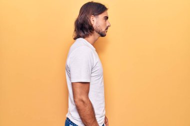 Sıradan kıyafetler giyen genç yakışıklı bir adam, rahat bir görünüm takınıyor kendine güvenen bir gülümsemeyle doğal bir yüz ifadesi takınıyor.. 