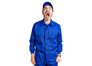 Orta yaşlı, yakışıklı, tamirci üniforması giyen sinirli ve sinirli sinirli sinirli, öfkeyle bağıran bir adam. öfke ve agresif konsept. 