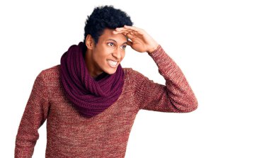 Genç Afro-Amerikan adam günlük kışlık süveter ve eşarp giyiyor. Çok mutlu ve tebessüm ediyor. arama kavramı. 