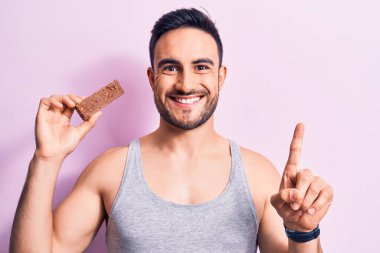 Sakallı, sakallı, enerji proteini yiyen, soyutlanmış pembe arka planda yaşayan yakışıklı bir adam bir fikir ya da soru işareti ile şaşırdı.