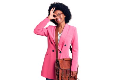 Genç Afro-Amerikalı kadın iş kıyafetleri ve deri çantalar içinde mutlu mesut gülümsüyor. 