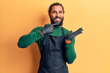 Genç Arap adam berber önlüğü takıyor kameraya hayret ediyor ve gülümsüyor.. 