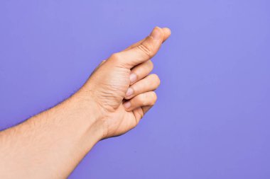 İzole edilmiş mor arka planda parmaklarını gösteren beyaz bir gencin eli parmak, iş ve reklamla boş bir alan tutuyor.