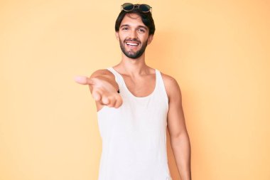 Yaz bakışı ve güneş gözlüğü takan yakışıklı İspanyol adam dostça bir selamlama ve hoş geldin hediyesi olarak gülümsüyor. başarılı iş. 