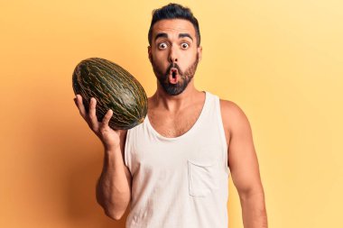 Karpuz tutan genç İspanyol adam korkmuş ve ağzı açık şaşkınlık içinde, inançsız yüz. 