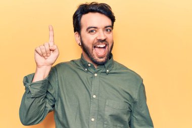 Gündelik kıyafetler giyen genç İspanyol adam başarılı bir fikirle işaret ediyor. Heyecanlı ve mutlu. Bir numara.. 