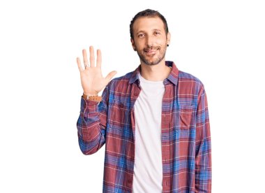 Gündelik kıyafetler giyen genç yakışıklı adam beş numarayı gösterip işaret ederken kendinden emin ve mutlu bir şekilde gülümsüyor.. 
