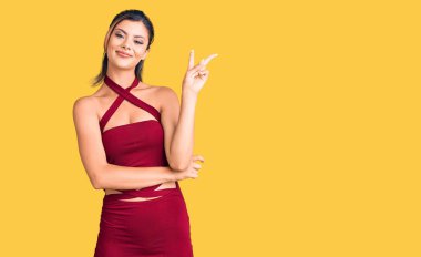 Gündelik kıyafetler giyen, gülen, kameraya göz kırpan, zafer işareti yapan genç ve güzel bir kadın. İki numara.. 