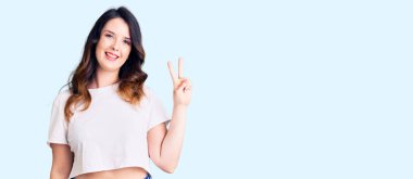 Güzel, genç, esmer, sıradan kıyafetler giyen, gülümseyen, kameraya göz kırpan, zafer işareti yapan bir kadın. İki numara.. 