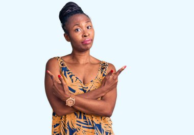 Gündelik giysiler giyen genç Afro-Amerikalı kadın her iki tarafı da parmaklarıyla işaret ediyor, farklı yönlere bakıyor. 