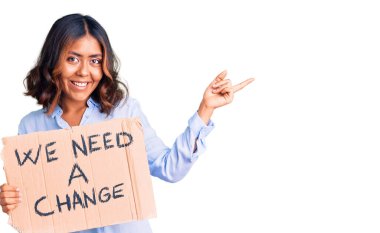 Genç, güzel, melez bir kadın elinde tutuyor Değişim bayrağına ihtiyacımız var Gülümseyen mutlu bir gülümsemeye 