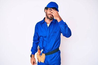 Kıvırcık saçlı yakışıklı genç adam ve ayı dokumacı üniformalı adam burnu ve gözleri ovuşturmaktan yorgun düşmüş yorgun ve başı ağrıyormuş. Stres ve hüsran kavramı. 