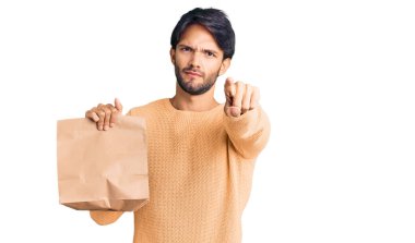 Yakışıklı, İspanyol asıllı, paket kağıdı tutan, kamerayı işaret eden, kendine güvenen, ciddi görünen bir adam. 