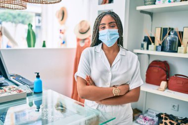 Genç Afrikalı Amerikalı kadın gülümsüyor. Perakende dükkanında Coronavirus güvenlik maskesi takıyor.