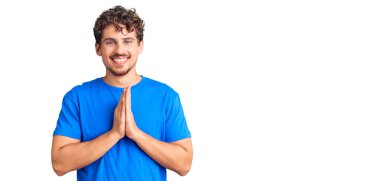 Kıvırcık saçlı, sıradan giyinen, elleriyle dua eden, affedilmek isteyen, kendine güvenen genç, yakışıklı bir adam.. 