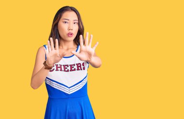 Ponpon kız üniforması giyen genç, güzel bir Çinli kız. Avuçlarını hareket ettiriyor. Korkmuş ve iğrenç bir ifadeyle reddediyor. Dur ve yasakla. 