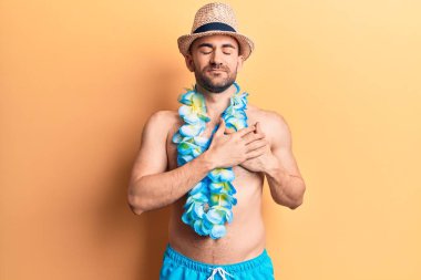 Genç, kel, mayo giymeyen, elleri göğsünde gülümseyen, yüzünde minnet dolu bir jest olan yakışıklı bir adam. sağlık kavramı. 