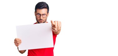 Elinde boş pankart tutan genç İspanyol adam kamerayı işaret ediyor ve sen kendine güvenen ciddi bir hareket yapıyorsun. 