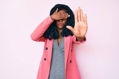 İş ceketi giyen güzel Afrikalı kadın ve gözlük takan, ellerle gözlerini kapayan ve üzgün ve korku ifadeleriyle jestleri durduran. utangaç ve olumsuz kavram. 