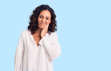 Orta yaşlı güzel bir kadın diş ağrısı ya da diş hastalığından dolayı ağzıyla dokunan sıradan bir kazak giyiyor. dişçi 