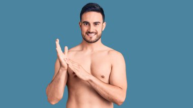 Mayo giyen genç yakışıklı adam alkışlıyor ve mutlu ve neşeli, gururlu elleri alkışlıyor. 