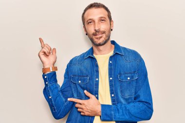 Gündelik kıyafetler giyen genç yakışıklı adam gülümseyerek mutlu bir şekilde elini ve parmağını kenarda gezdiriyor. 