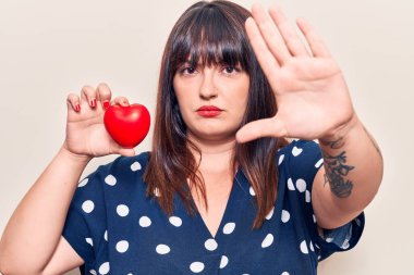 Kalbini açık tutan genç ve iri bir kadın dur işareti yapıyor. Ciddi ve kendinden emin bir ifadeyle, savunma hareketi yapıyor. 