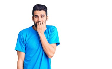 Sakallı, sıradan tişörtlü, stresli ve gergin görünen dudakları tırnak yiyen genç yakışıklı bir adam. anksiyete. 