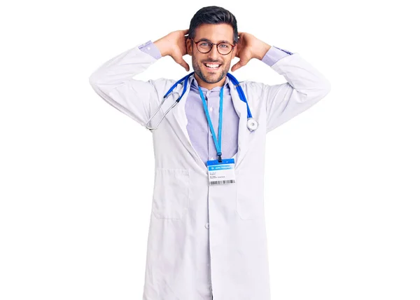 医者の制服を着た若いヒスパニック系の男と聴診器リラックスしてストレッチ 腕と手頭と首の後ろに笑顔幸せ — ストック写真