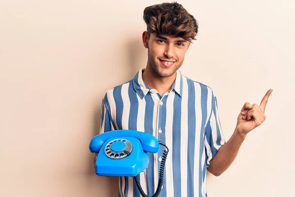 Νεαρός Ισπανός Κρατώντας Ένα Παλιό Τηλέφωνο Χαμογελώντας Χαρούμενος Δείχνοντας Χέρι — Φωτογραφία Αρχείου