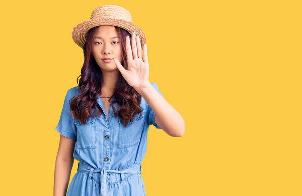年轻美丽的中国姑娘戴着夏帽 不停地用手掌唱歌 用消极而严肃的手势警告人 — 图库照片