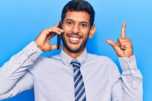Genç latin adam akıllı telefondan konuşuyor. Bir fikir veya soruyla gülümsüyor. Mutlu bir yüzle işaret ediyor. 