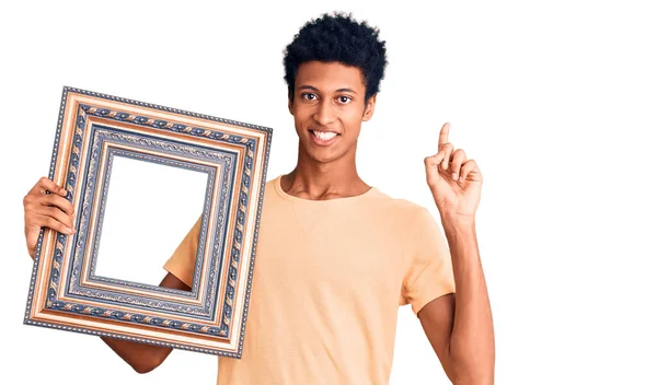 Young African American Man Holding Empty Frame Surprised Idea Question — Stock Photo, Image