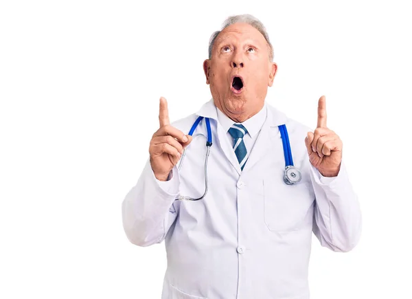 Starszy Przystojny Siwowłosy Mężczyzna Płaszczu Lekarskim Stetoskopie Zdumiony Zaskoczony Patrząc — Zdjęcie stockowe
