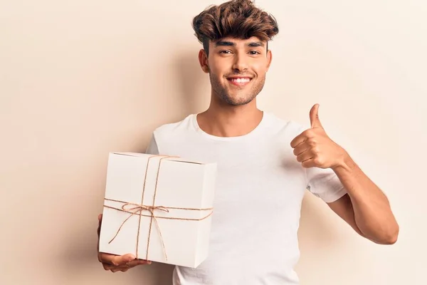 Молодий Іспаномовний Чоловік Тримає Подарунок Усміхнений Щасливий Позитивний Великий Палець — стокове фото