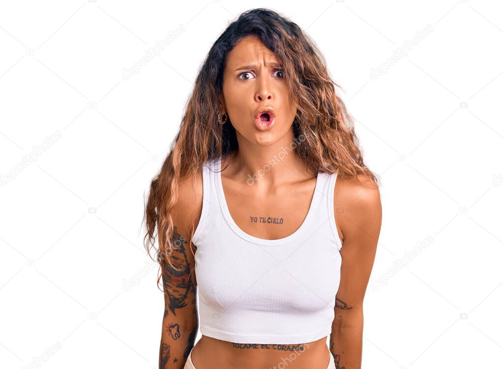 Young hispanic woman with tattoo wearing casual clothes scared and amazed with open mouth for surprise, disbelief face 