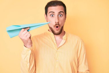 Elinde kağıt uçak tutan genç yakışıklı adam şaşıracak şekilde ağzı açık kalmış, korkmuş ve hayrete düşmüştü. 