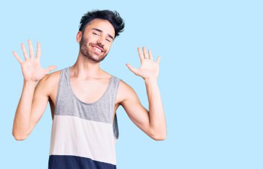 Gündelik kıyafetler giyen genç İspanyol adam on numarayı gösterip işaret ederken kendinden emin ve mutlu bir şekilde gülümsüyor.. 