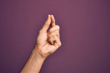 İzole edilmiş mor arka planda parmaklarını gösteren beyaz bir gencin eli parmak, iş ve reklamla boş bir alan tutuyor.