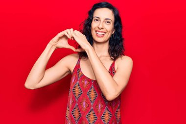 Gündelik kıyafetler giyen, aşık gülümseyen, elleriyle kalp sembolü yapan genç, güzel İspanyol bir kadın. romantik kavram. 