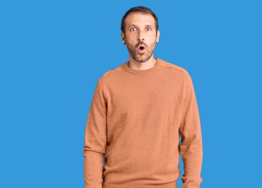 Gündelik kıyafetler giyen genç, yakışıklı bir adam. Şaşırmış ve korkmuş bir ifade, korku ve heyecanlı bir yüz ifadesi.. 